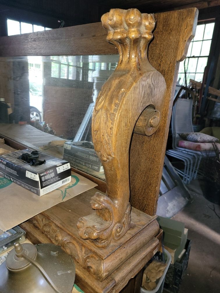 Vintage wooden furniture detail with ornate carving, set in a cluttered room.